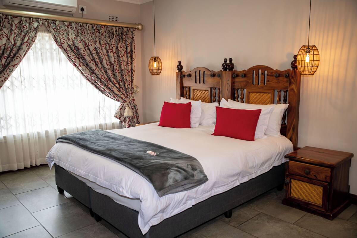 A neatly made bed with white and red bedding, a wooden headboard, and two bedside lamps.