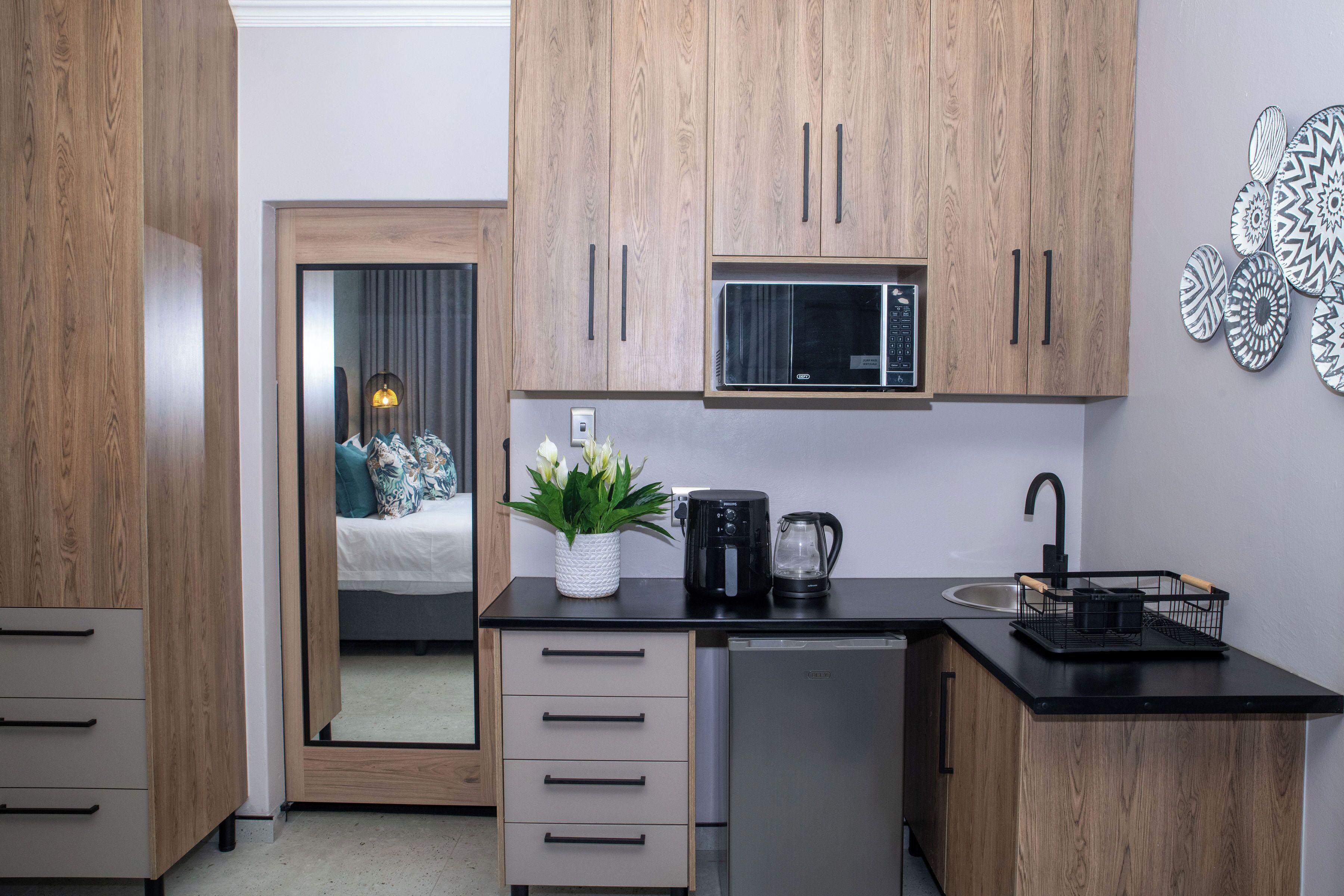 A compact kitchen with wooden cabinets, a microwave, a coffee maker, and a sink.