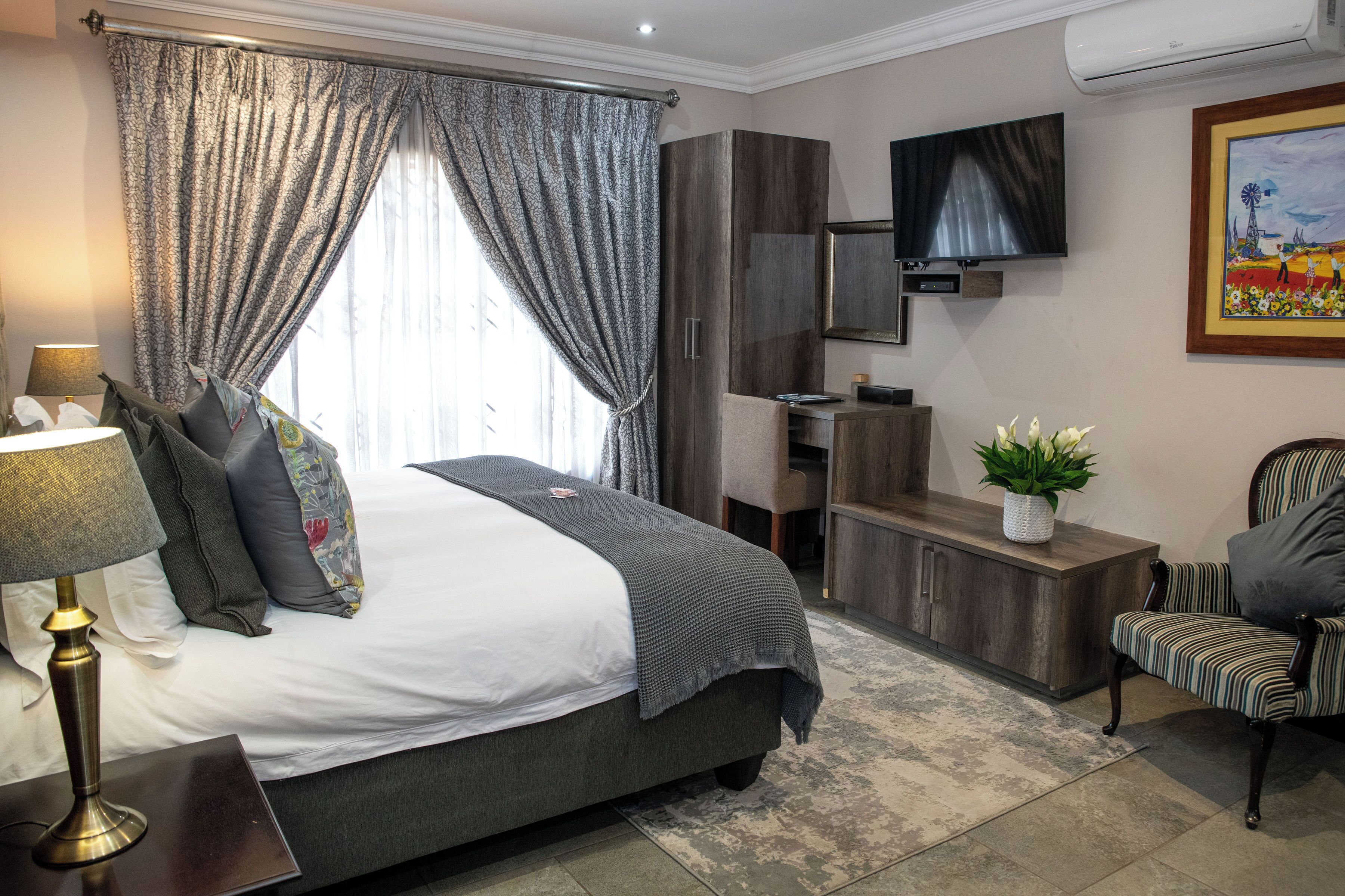 Une chambre d’hôtel comprenant un lit, un bureau, une télévision, une armoire et une chaise.