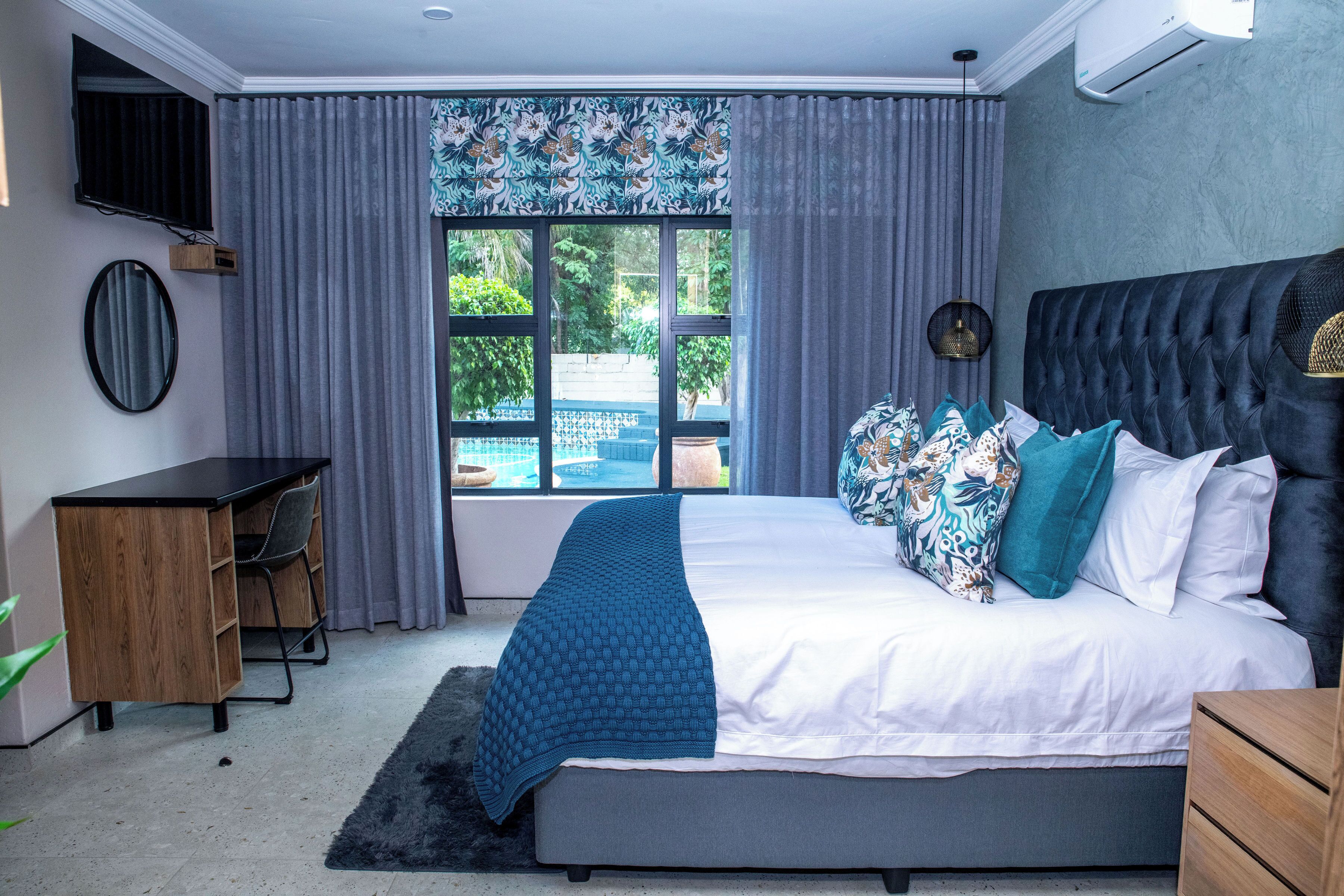 Un dormitorio con una cama grande, un escritorio y una ventana con cortinas.