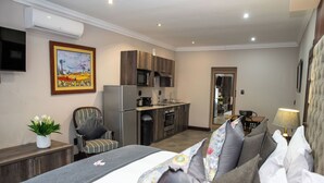 Una habitación de hotel moderna con cama, sofá, mesa de comedor y kitchenette.