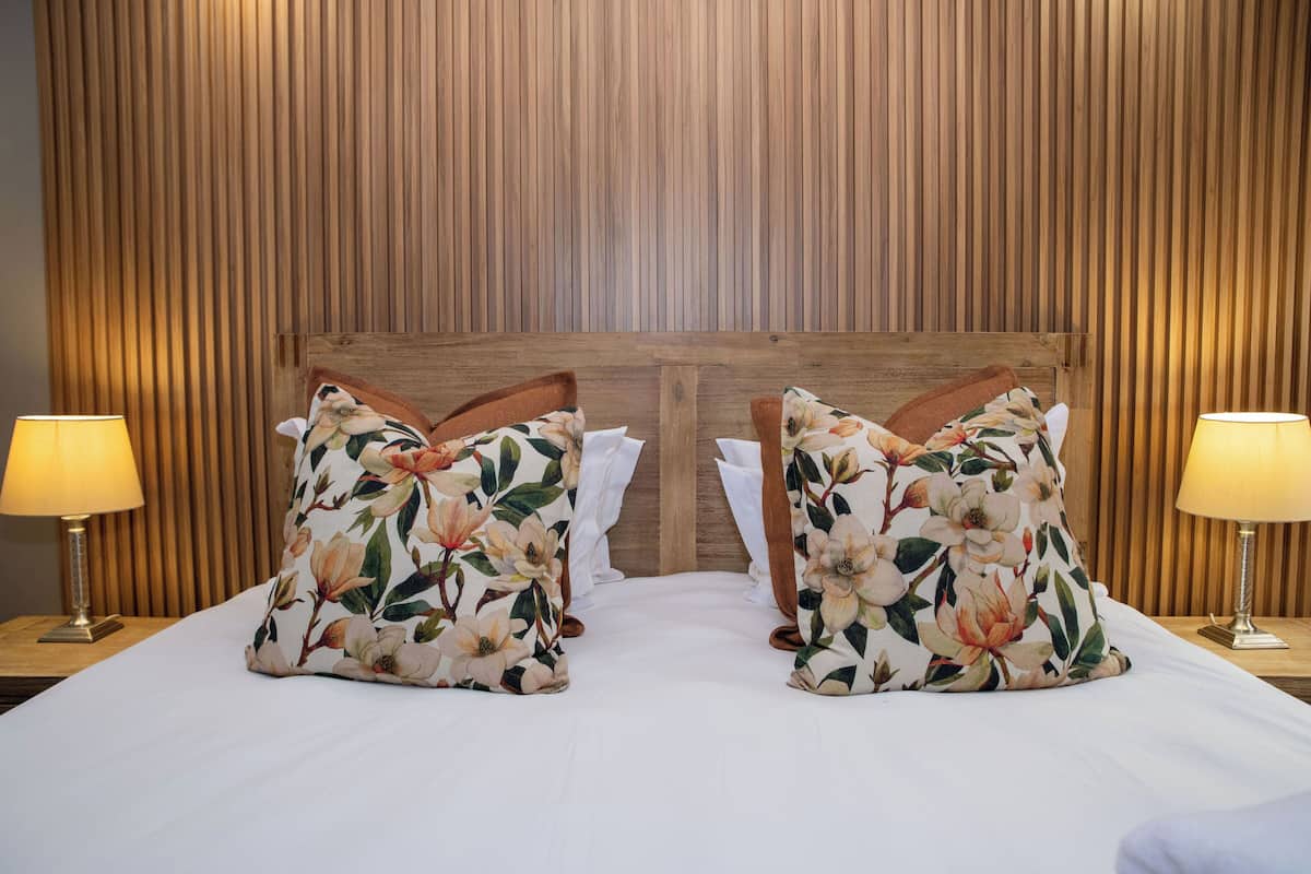 A neatly made bed with floral pillows and two bedside lamps.