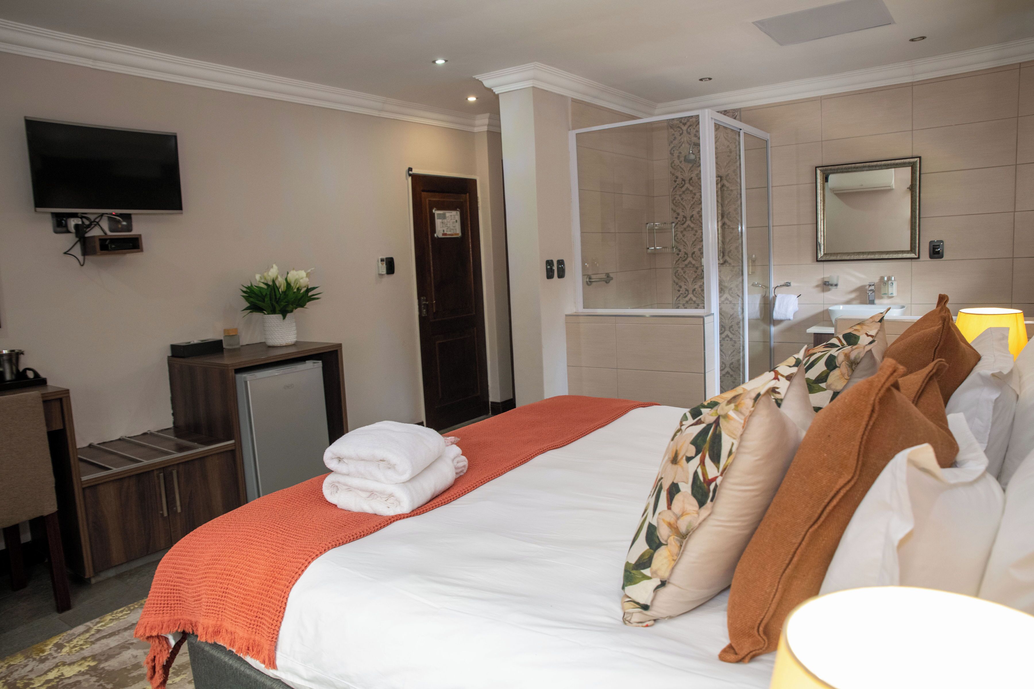 Una habitación de hotel con cama, televisión, escritorio, ducha y baño.