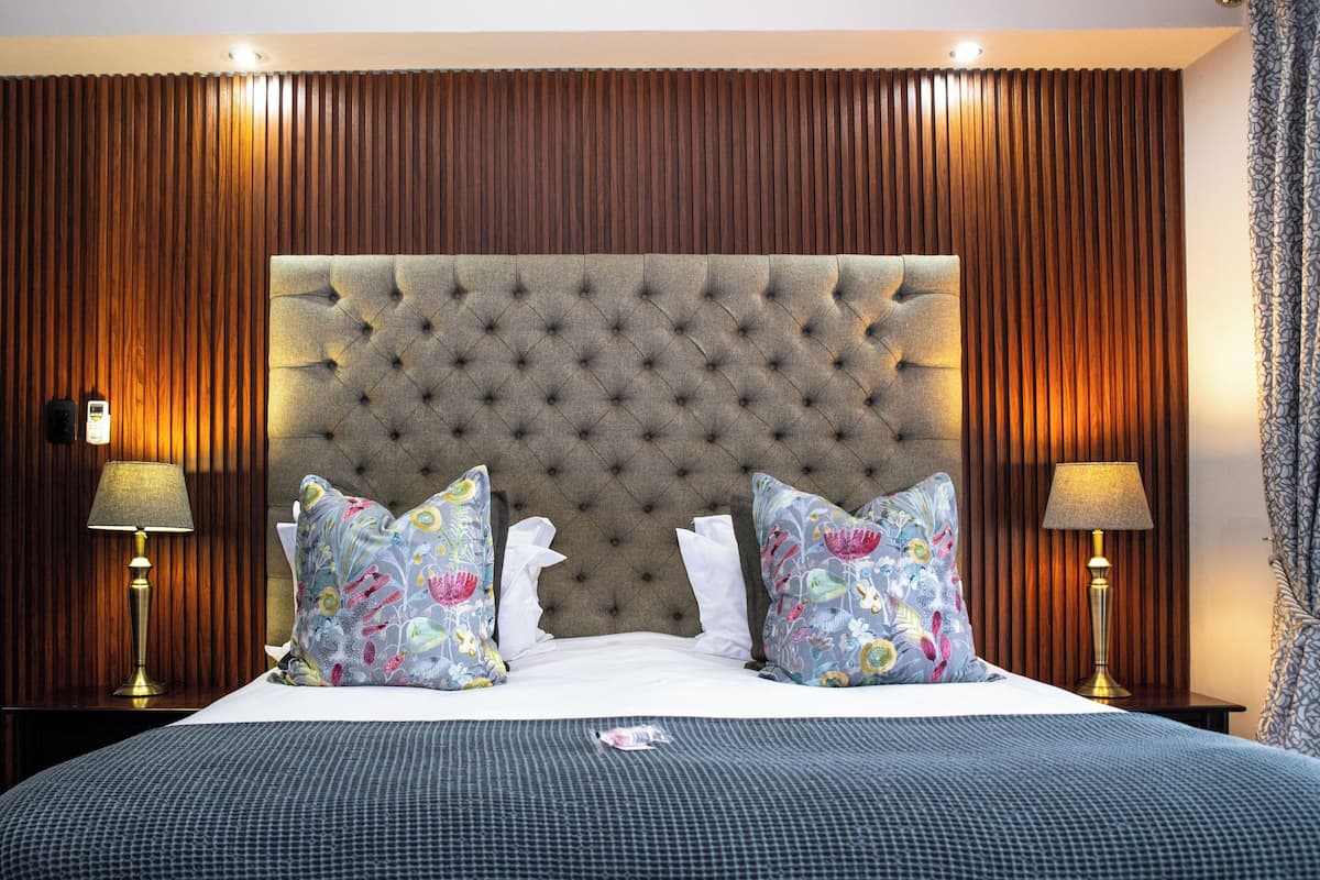 A neatly made bed with a tufted headboard, two patterned pillows, and a matching bedspread.