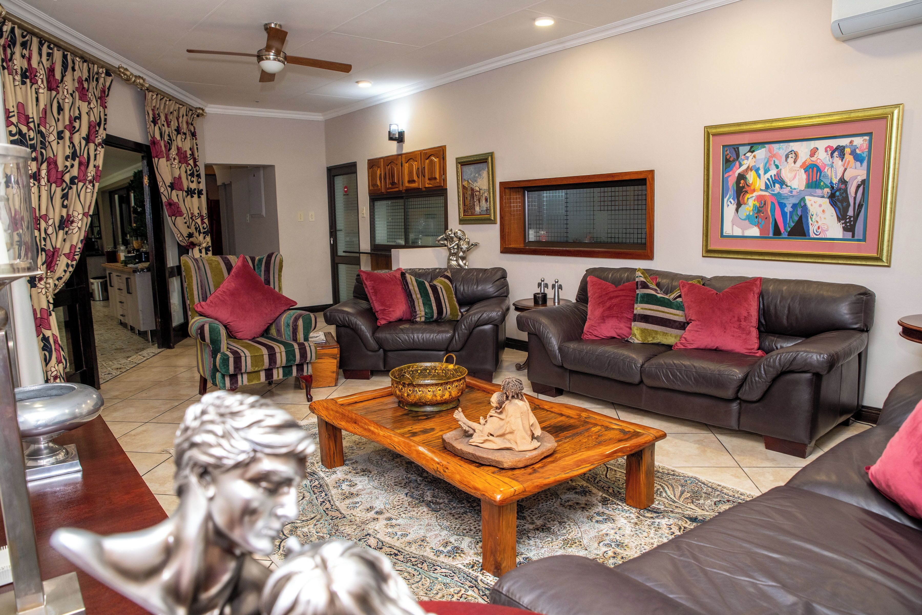 A living room with leather sofas, a wooden coffee table, and a statue.