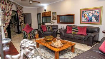 A living room with leather sofas, a wooden coffee table, and a statue.