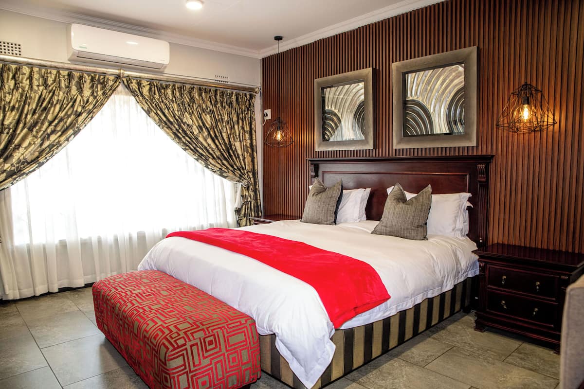 A large bed with a red and white bedspread, a wooden headboard, and two wall-mounted picture frames.