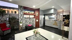 A modern hotel lobby with a reception desk, seating area, and a decorative wall. - Little Rock Cebu (Lapu-Lapu)