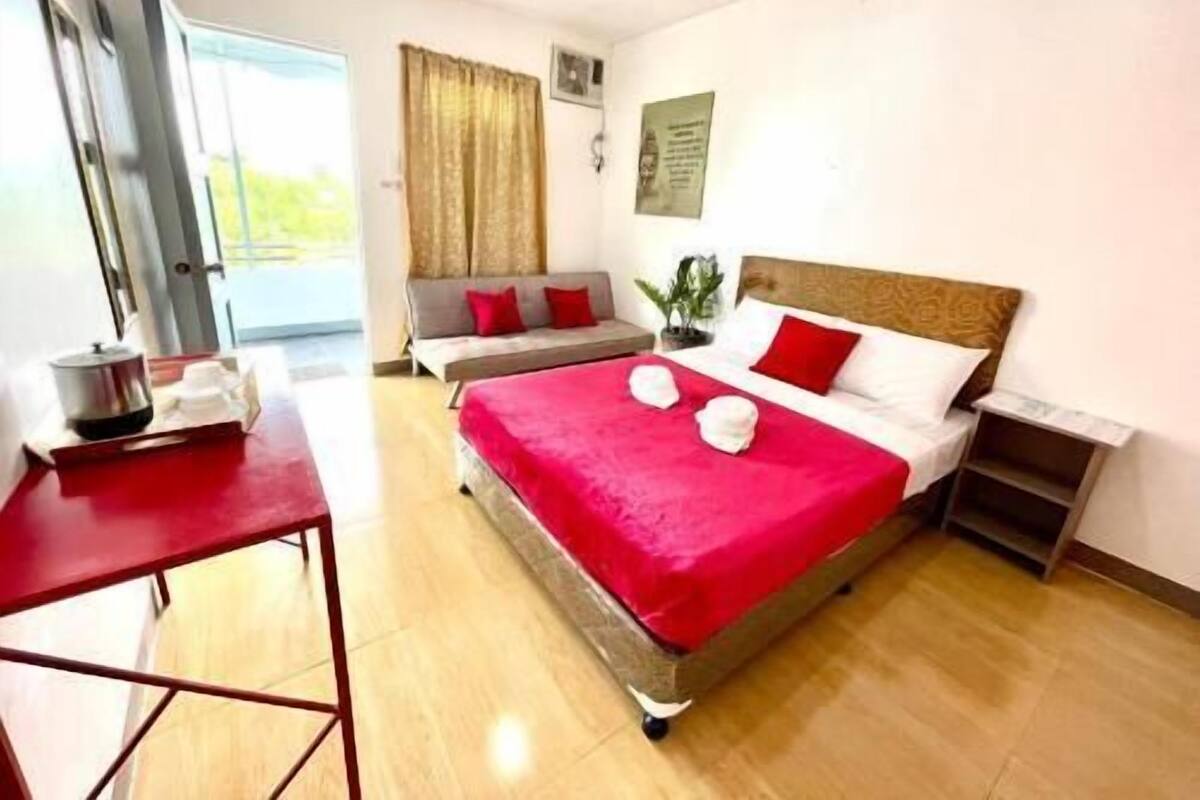 A hotel room with a bed, a sofa, a small table, and a nightstand.