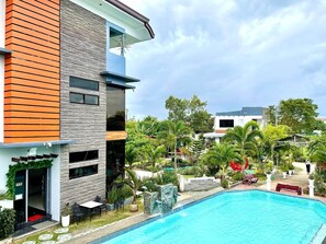 A modern building with a swimming pool, surrounded by lush greenery and palm trees. - Little Rock Cebu (Lapu-Lapu)