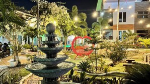 A nighttime outdoor area with a multi-tiered fountain, potted plants, and a red spherical sculpture. - Little Rock Cebu (Lapu-Lapu)