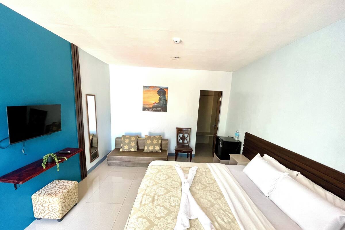 A hotel room with a large bed, a TV, a desk, and a chair.