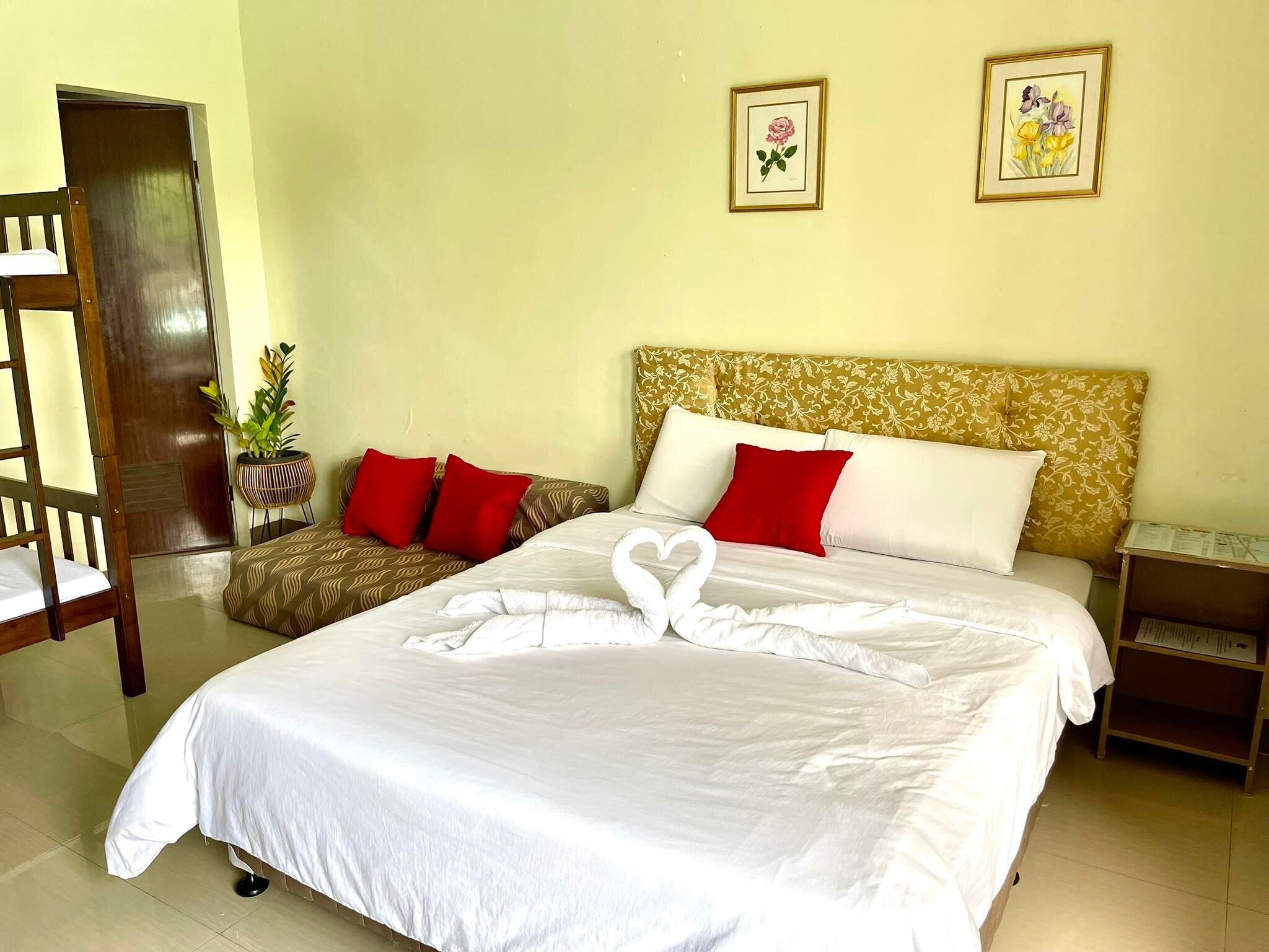 A hotel room with a bed, two pillows, a nightstand, a wooden chair, and two framed pictures on the wall.