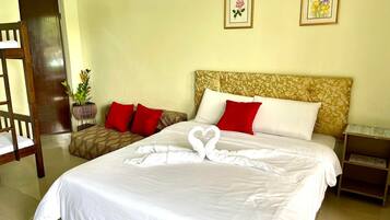 A hotel room with a bed, two pillows, a nightstand, a wooden chair, and two framed pictures on the wall.
