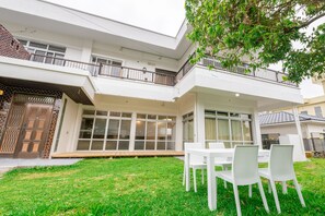 A two-story house with a covered patio, large windows, and a grassy lawn. - Paraiso de Motobu (Motobu)