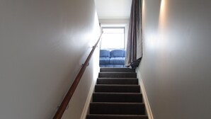 Eine Treppe führt zu einem Raum mit einem blauen Sofa und einem Fenster.