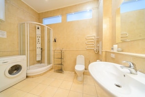 A modern bathroom with a glass-enclosed shower, a toilet, a sink, and a washing machine. - Apartments Kreshchatik 27-32 (Kyiv)