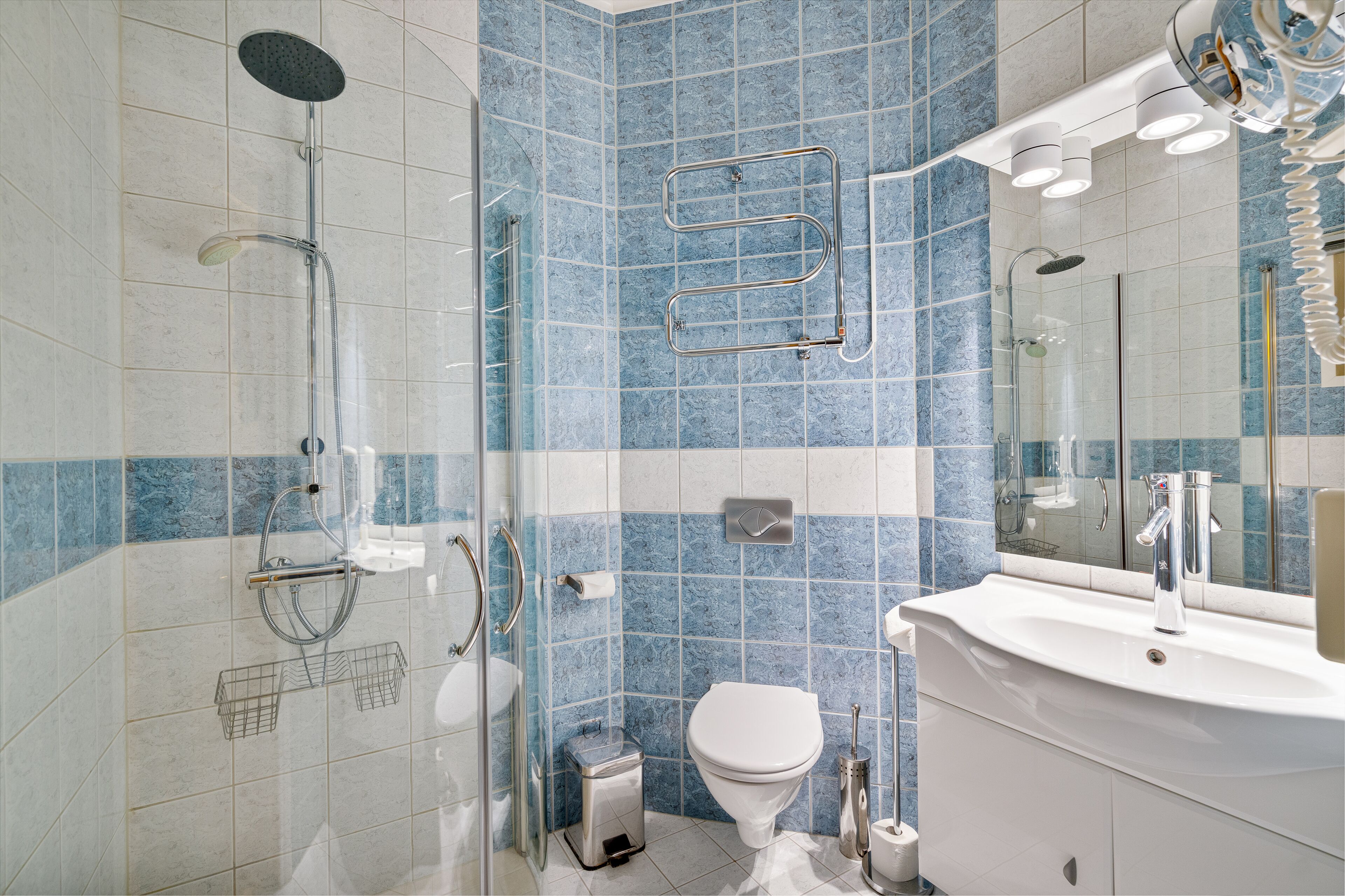Un baño moderno con ducha de vidrio, lavamanos blanco y un inodoro.