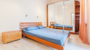 A bedroom with a bed, wooden dresser, and a large mirror cabinet. - Apartment Kreschatik Luteranskaya (Kyiv)