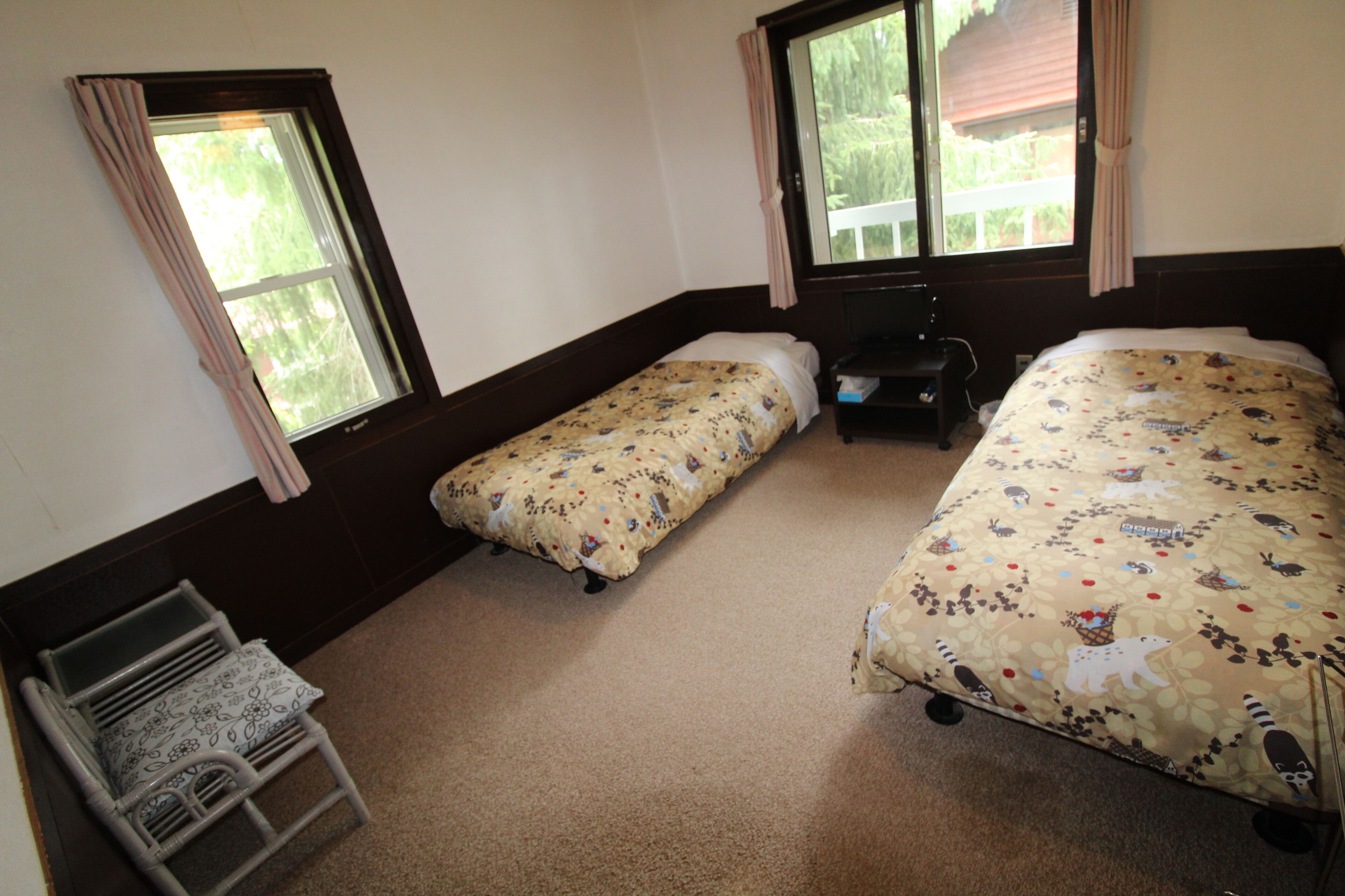 Ein Zimmer mit zwei Einzelbetten, einem kleinen Tisch und einem Stuhl.
