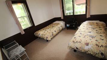 Ein Zimmer mit zwei Einzelbetten, einem kleinen Tisch und einem Stuhl.