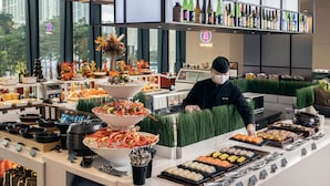 Un buffet proposant une variété de plats, avec un membre du personnel qui s’en occupe.