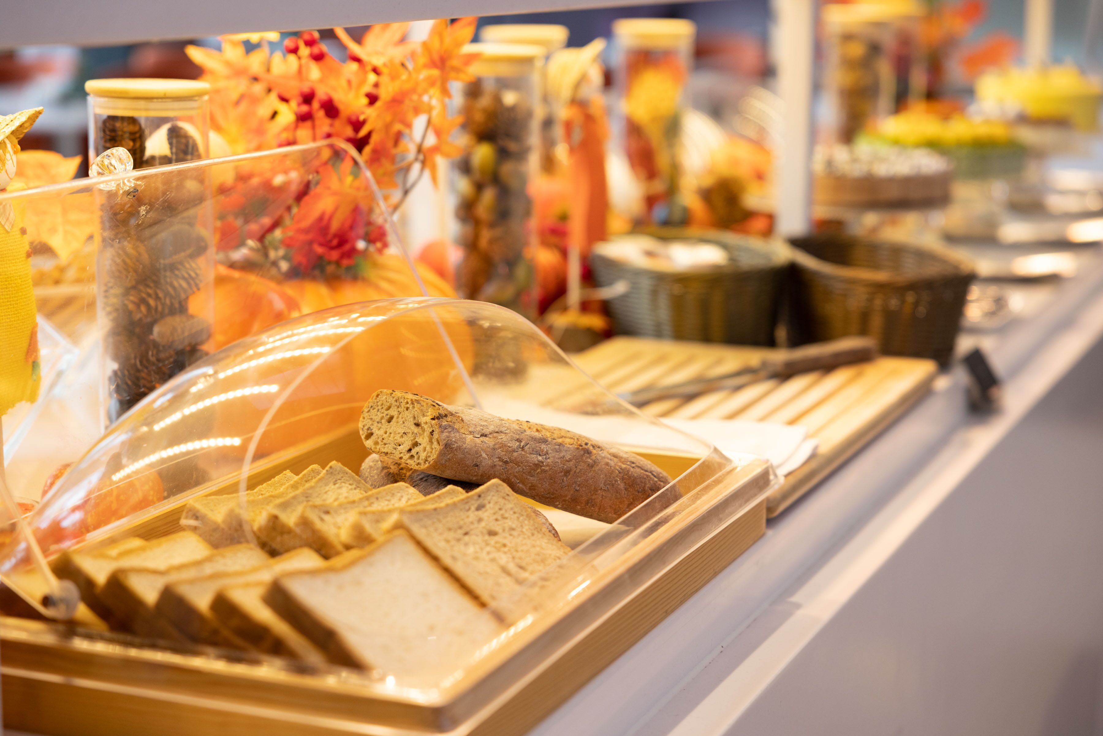 A buffet with various food items, including bread and pastries, displayed in a clear plastic cover.