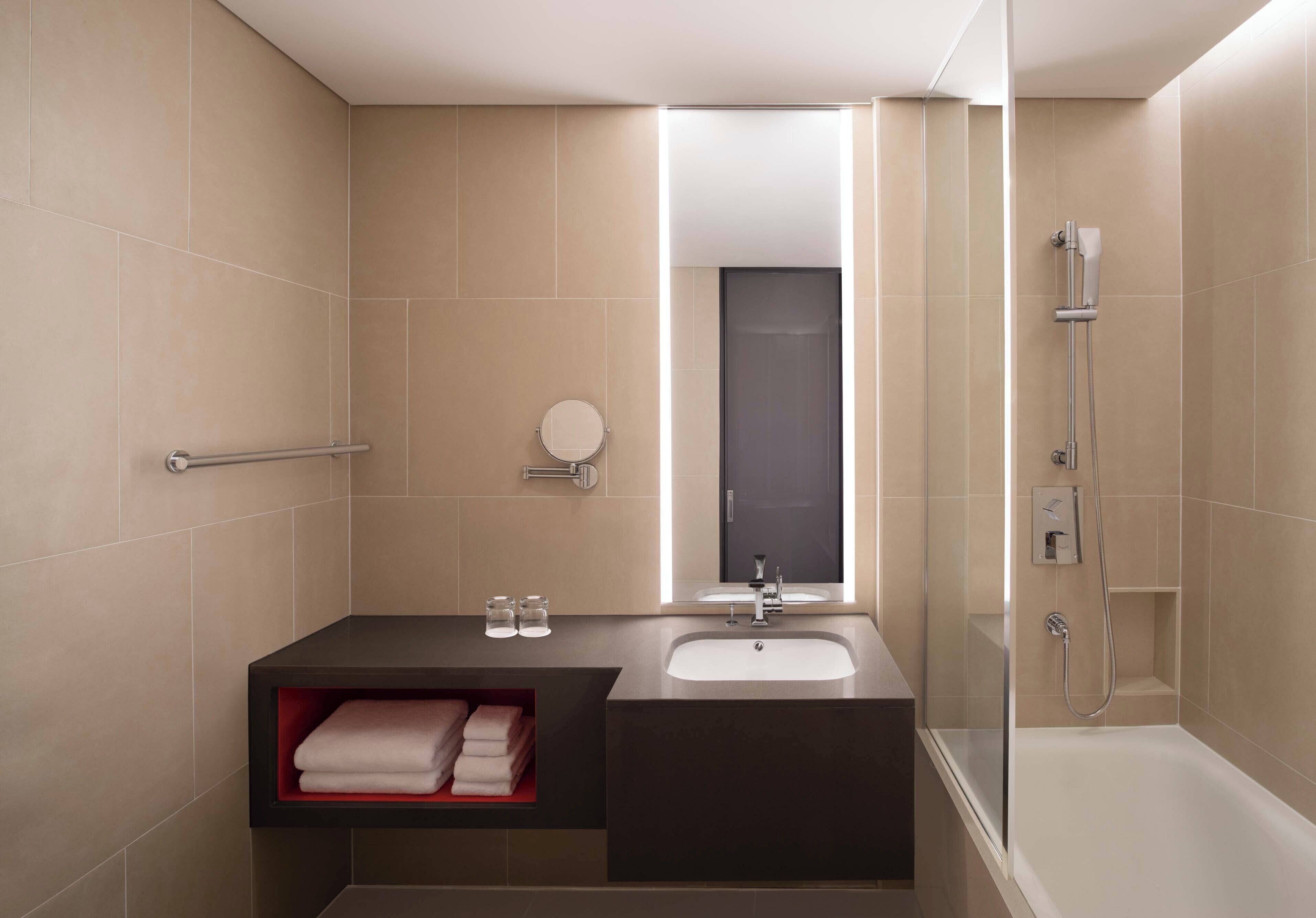 A modern bathroom with a vanity, sink, mirror, and shower.