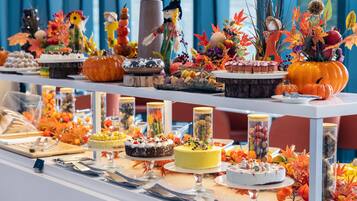 Una mesa de bufé con diversos postres y adornos, incluyendo calabazas y hojas de otoño.