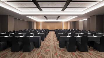 A conference room with multiple tables and chairs, a patterned carpet, and a ceiling with recessed lighting.