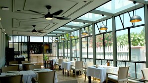 A restaurant with high ceilings, large windows, wicker chairs, and tables set for dining. - Egehan Butik Otel (Ortaca)