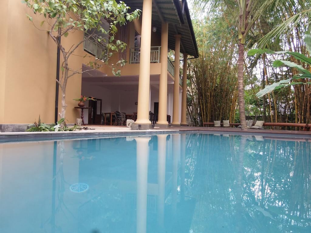 A swimming pool with a building in the background, surrounded by trees.