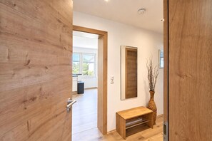A modern interior with a wooden door, a bench, a mirror, and a vase. - Holiday Home in Aschau by Zillertal Alps (Aschau)
