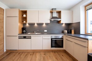 Una cucina moderna con elettrodomestici integrati, pavimento in legno e una finestra che offre luce naturale.