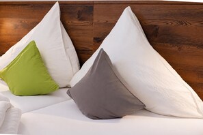 Un lit avec des oreillers aux couleurs blanche, verte et grise.