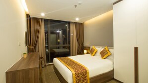 A hotel room with a bed, a desk, and a window with curtains. - Citypoint Apartment (Da Nang)