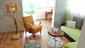 A living room with a yellow armchair, a round ottoman with a black and white pattern, a small table with a candle, and a green sofa with patterned cushions. - LUCIJA 1 - Enjoy the Rovinj (Rovinj)