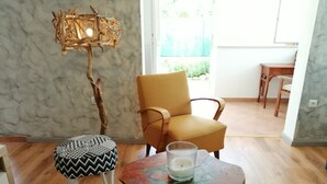 A room with a wooden floor, a yellow armchair, a small round table with a candle, and a patterned ottoman. - LUCIJA 1 - Enjoy the Rovinj (Rovinj)