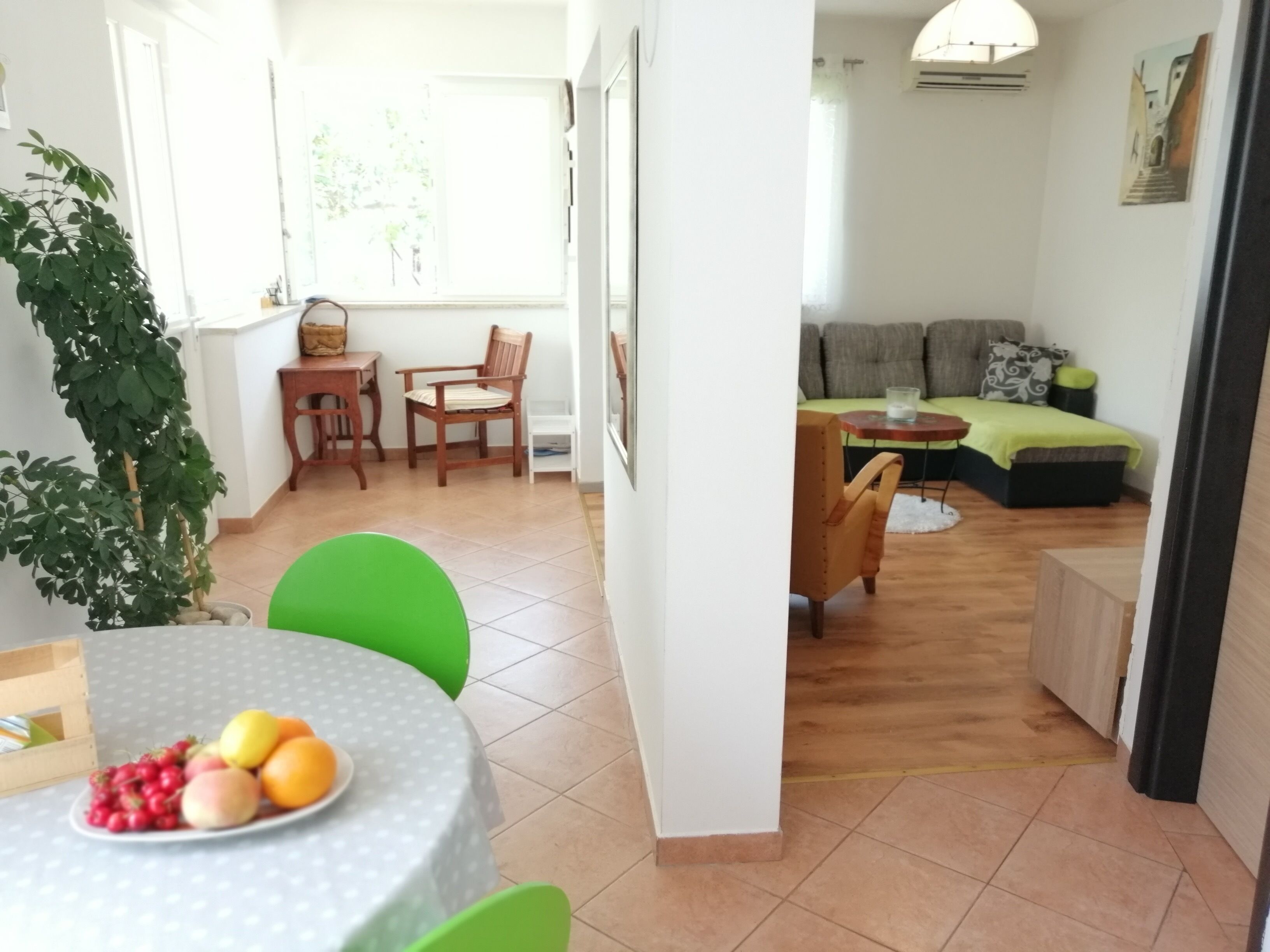 A bright living room with a dining area, a sofa, and a table with fruit.