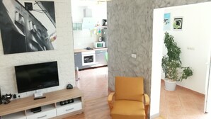 A living room with a TV, a sofa, a dining area with a table, and a kitchen in the background. - LUCIJA 1 - Enjoy the Rovinj (Rovinj)