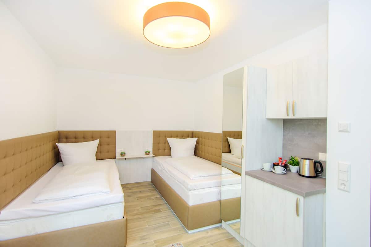 A hotel room with two beds, a small kitchenette, and a mirror.