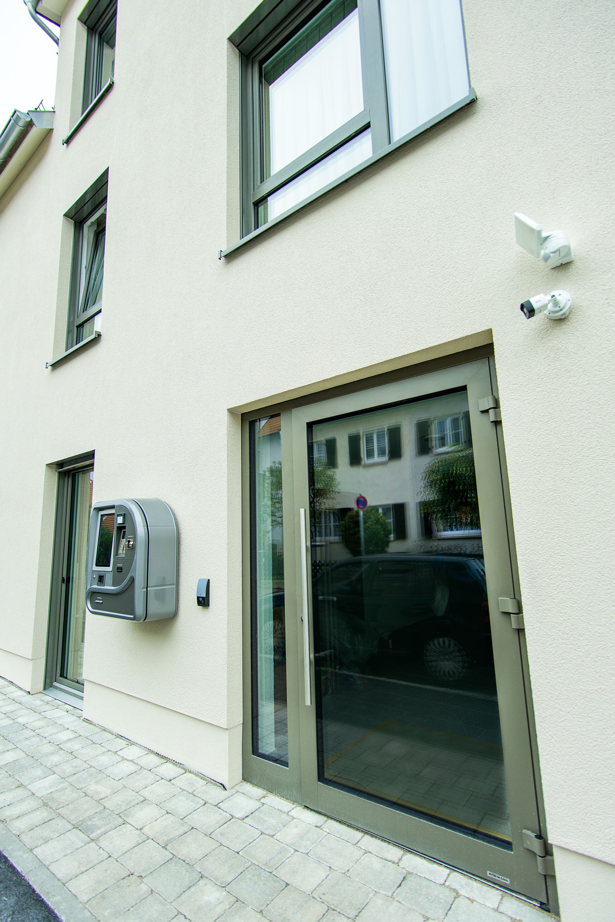 Un bâtiment doté d’une grande porte vitrée, d’une caméra de surveillance et d’une boîte aux lettres.
