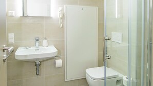 A modern bathroom with a sink, mirror, toilet, and glass-enclosed shower. - Hotel Filderhof Reutlingen (Reutlingen)