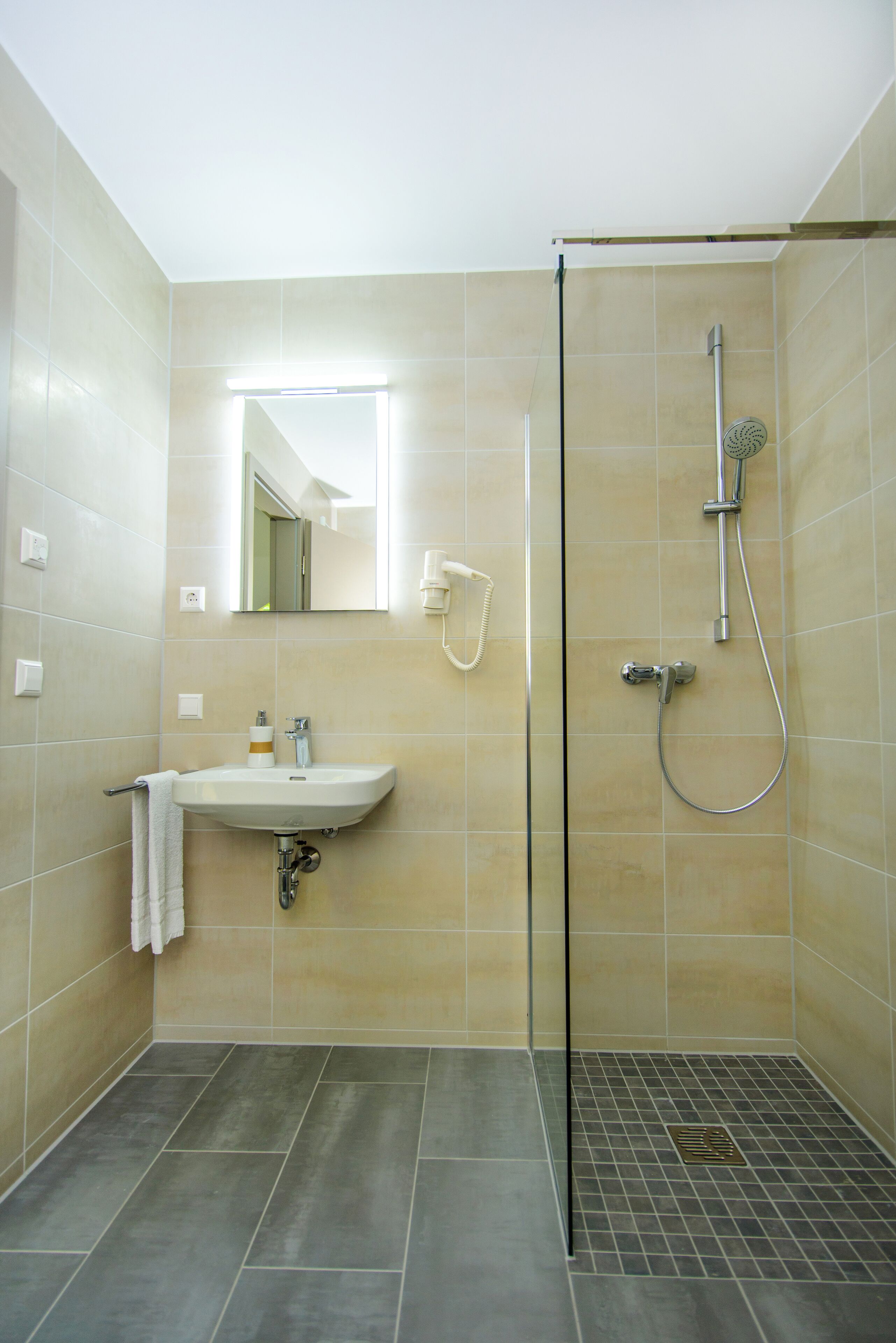 A bathroom with a sink, mirror, and shower.