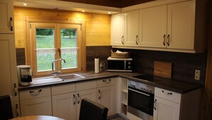 A modern kitchen with white cabinets, a stainless steel oven, and a window overlooking a garden. - Where nature lives ... enjoy your vacation. (Drognitz)