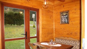 A wooden interior with a dining table, chairs, and a bench. There is a window with a view of greenery outside. - Where nature lives ... enjoy your vacation. (Drognitz)