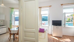 Una stanza con un letto, una televisione, un'area pranzo e vista sul mare.