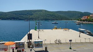 Una passeggiata sul lungomare con vista su barche sull'acqua, un rastrelliera per biciclette e una chiosco con un ombrellone.