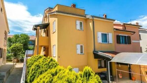 A two-story building with a yellow facade, multiple windows, and a visible garage area. - Holiday house Vesna for relaxed vacation (Medulin)