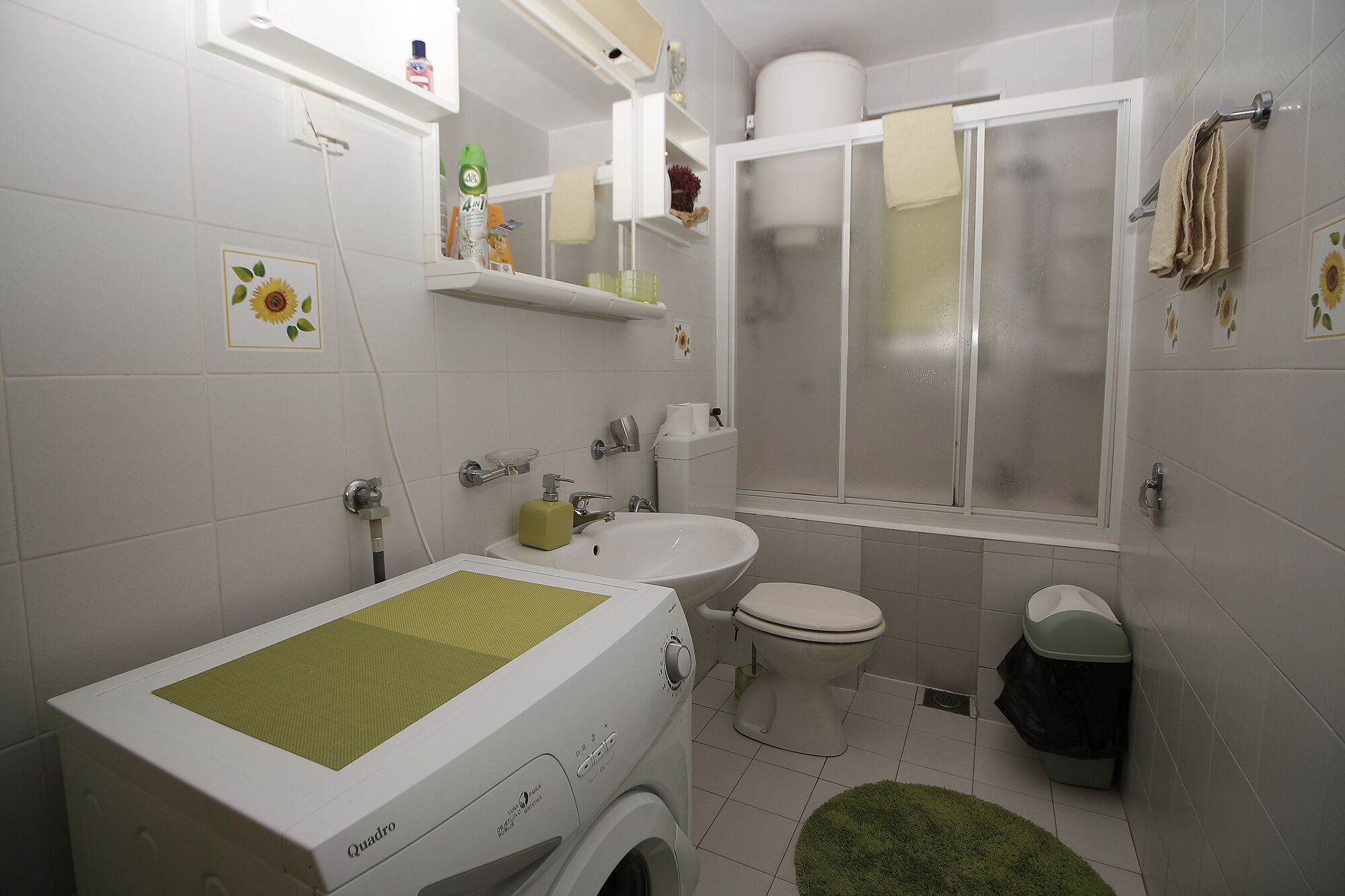 A bathroom with a washing machine, toilet, and a shower area.
